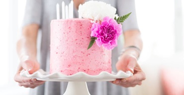 detail of woman carrying pink cake on serving plate