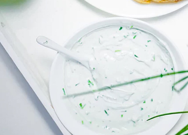 dip with green herbs in a white bowl from overhaed